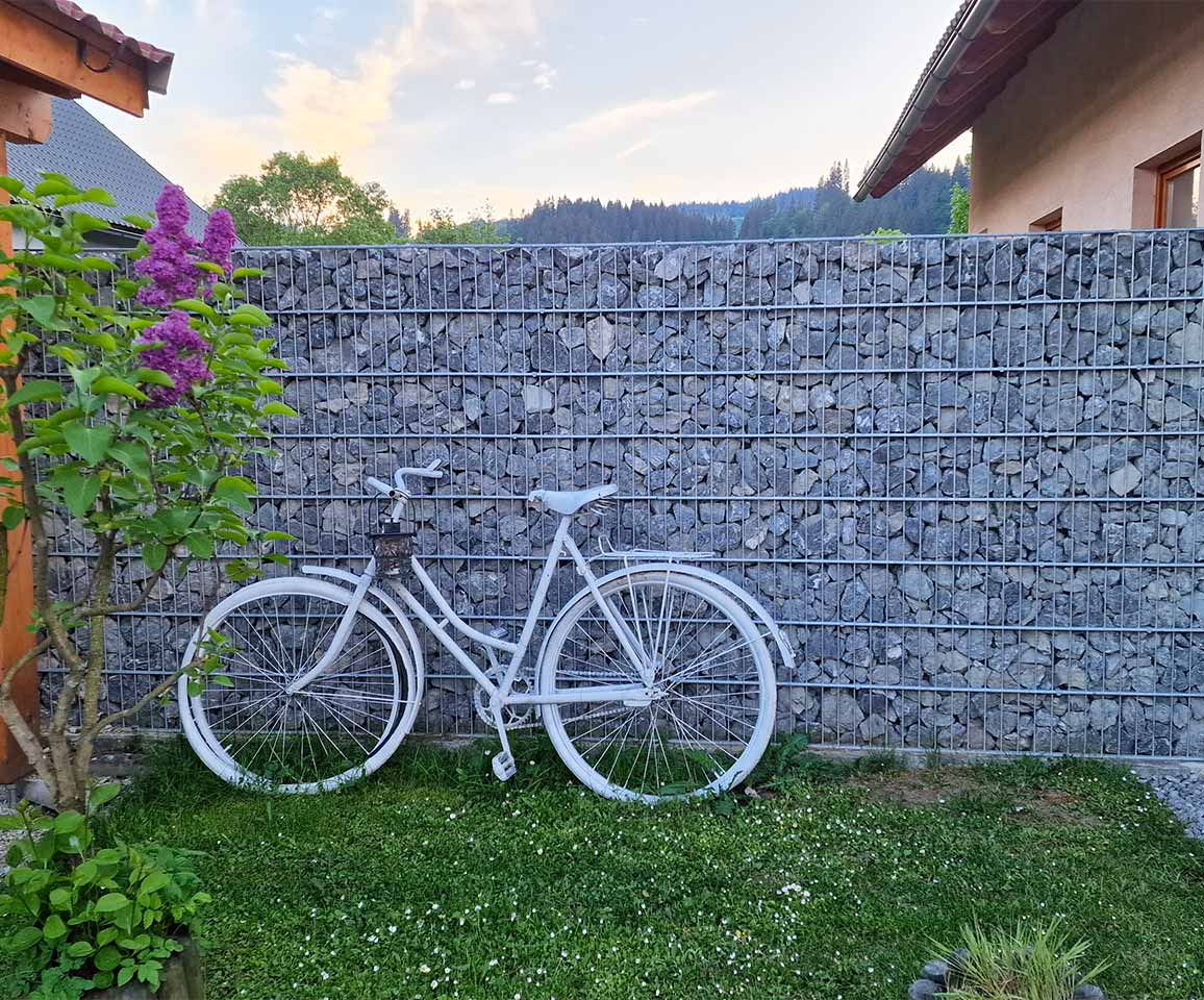 záhradná dekorácia bicykel opretá o gabionový plot