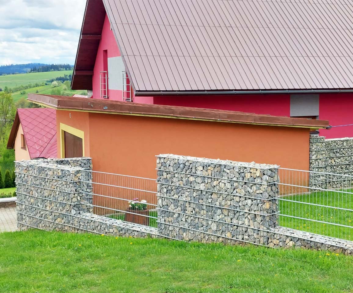 oranžový dom obklopený gabionovým plotom s 2d panelmi